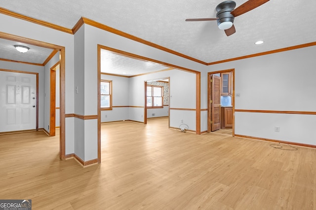 spare room featuring baseboards, a ceiling fan, light wood-style floors, and a textured ceiling