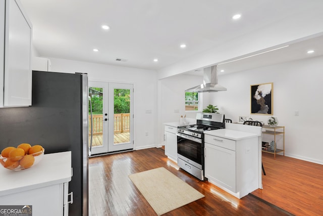 kitchen with visible vents, white cabinets, wall chimney range hood, stainless steel appliances, and french doors
