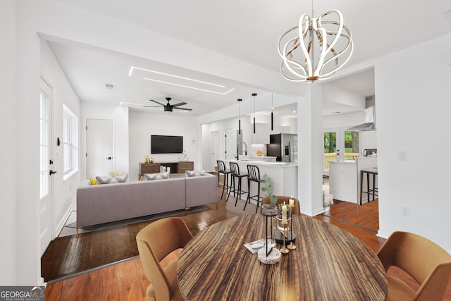 dining room featuring visible vents, ceiling fan with notable chandelier, baseboards, and wood finished floors