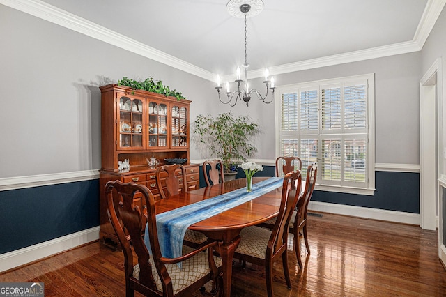 dining space with an inviting chandelier, ornamental molding, wood finished floors, and baseboards