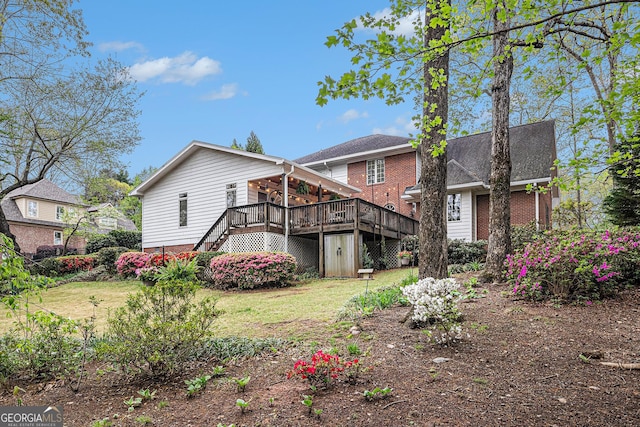 back of property featuring stairway, a lawn, brick siding, and a deck