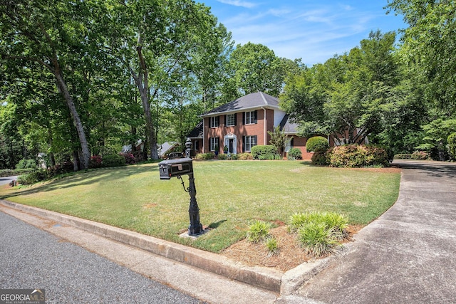 colonial inspired home featuring brick siding and a front yard