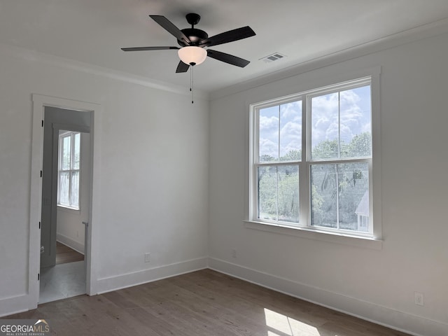 unfurnished room featuring baseboards, plenty of natural light, wood finished floors, and visible vents