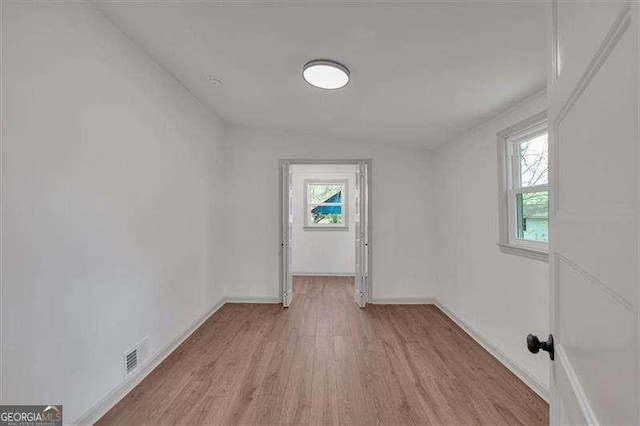 empty room featuring baseboards, plenty of natural light, and light wood-style floors
