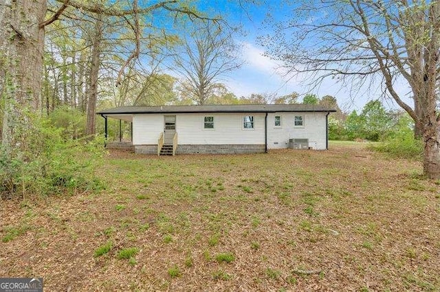 back of house featuring entry steps and a lawn