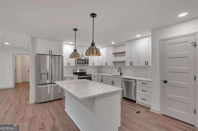kitchen featuring stainless steel appliances, white cabinetry, a sink, and open shelves