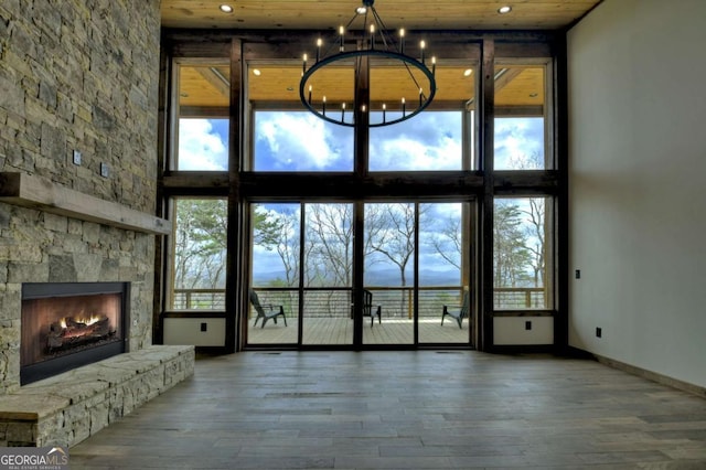768 Cherokee Cir, Ellijay, GA 30540 - unfurnished living room featuring a notable chandelier, a high ceiling, a stone fireplace, and wood finished floors