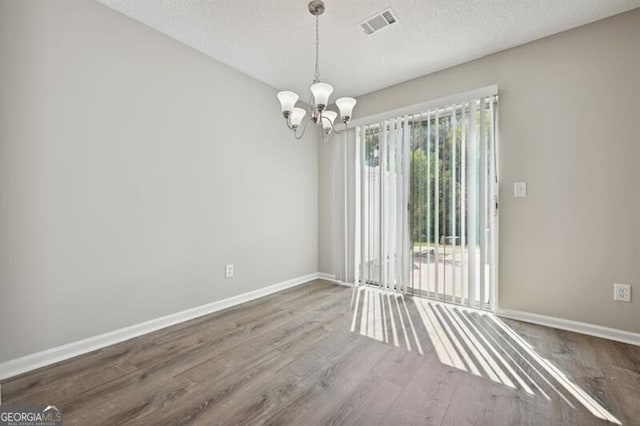 1575 April Ln, Morrow, GA 30260 - unfurnished room with a notable chandelier, baseboards, a textured ceiling, visible vents, and wood finished floors