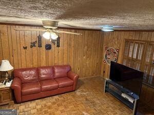 4528 Newcastle Cir, Lithonia, GA 30038 - living area with wood walls, a ceiling fan, and a textured ceiling