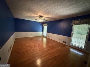 4528 Newcastle Cir, Lithonia, GA 30038 - empty room featuring a ceiling fan, wood finished floors, wainscoting, and a textured ceiling