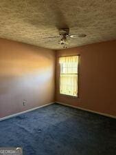 4528 Newcastle Cir, Lithonia, GA 30038 - empty room with dark colored carpet and ceiling fan