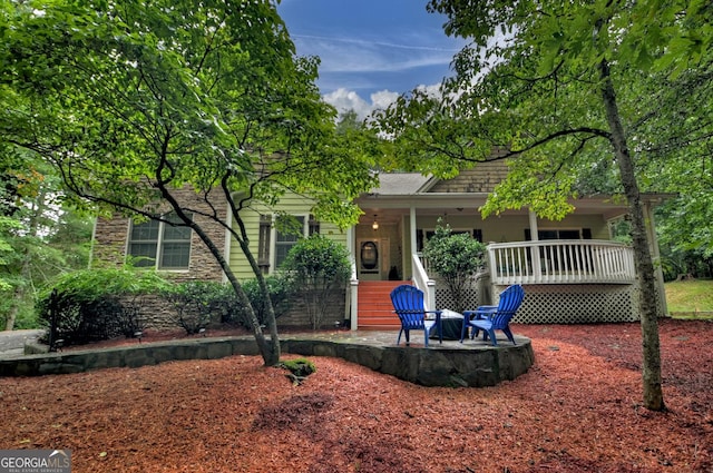 view of front facade featuring roof with shingles, a patio area, and stone siding