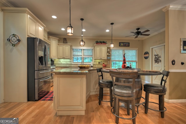 kitchen featuring a center island, cream cabinets, stainless steel fridge, and ceiling fan