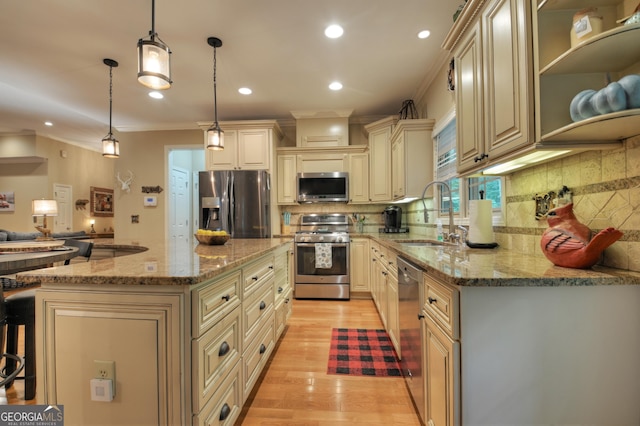 kitchen featuring a sink, appliances with stainless steel finishes, light wood-style floors, cream cabinetry, and light stone countertops