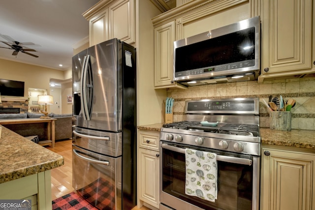 kitchen featuring stainless steel appliances, open floor plan, and cream cabinetry