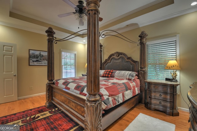 bedroom with a tray ceiling, crown molding, and wood finished floors