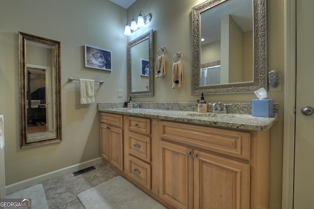 bathroom with baseboards, double vanity, an enclosed shower, visible vents, and a sink