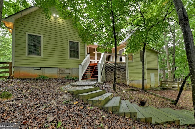 back of house featuring stairway, crawl space, a wooden deck, and fence