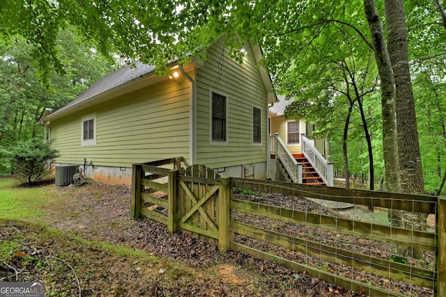 view of property exterior with central AC unit, fence, a gate, and stairs