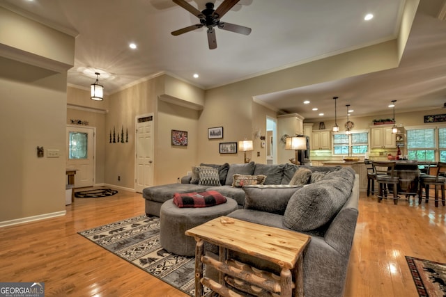 living room with crown molding, light wood-style flooring, and a ceiling fan