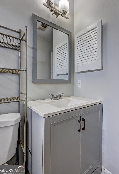 half bathroom featuring toilet, vanity, and visible vents
