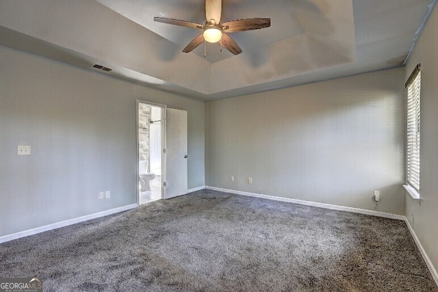 spare room with visible vents, a ceiling fan, a tray ceiling, and carpet