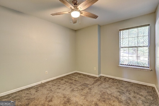 carpeted spare room featuring baseboards and a ceiling fan