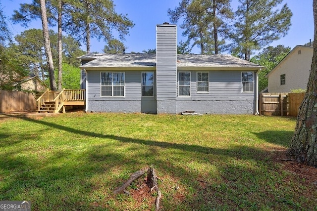 rear view of property featuring a fenced backyard, a wooden deck, and a lawn