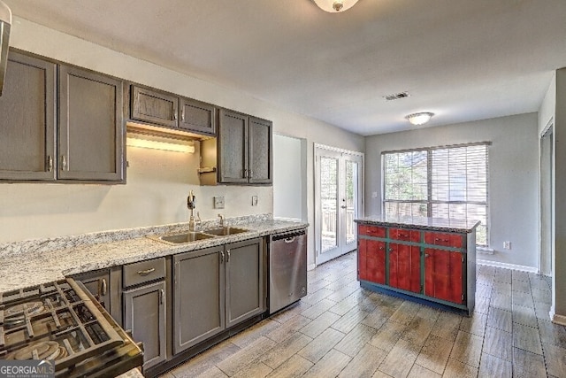 kitchen featuring cooktop, visible vents, light wood finished floors, dishwasher, and a sink