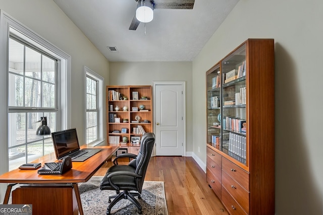 office with light wood-style floors, visible vents, baseboards, and ceiling fan
