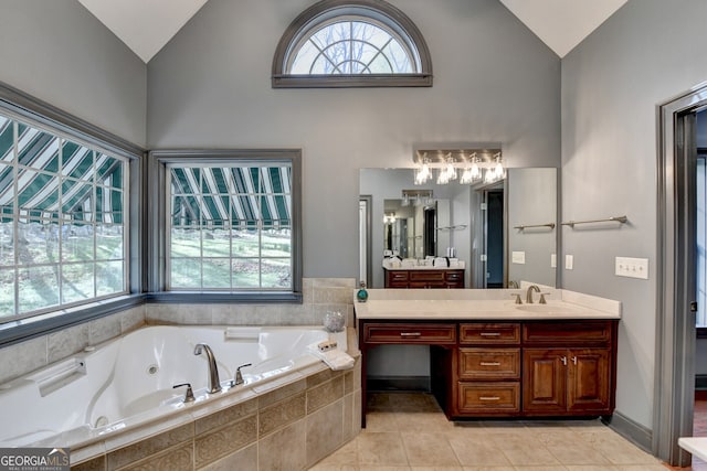bathroom with a wealth of natural light, vanity, vaulted ceiling, and a tub with jets