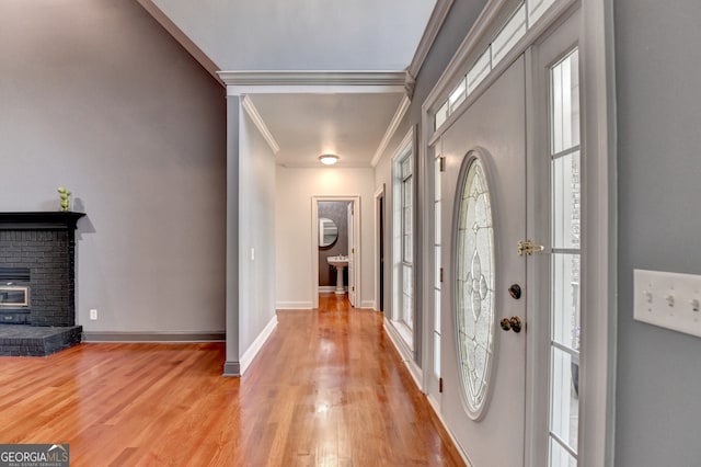 entrance foyer with plenty of natural light, light wood-type flooring, baseboards, and crown molding