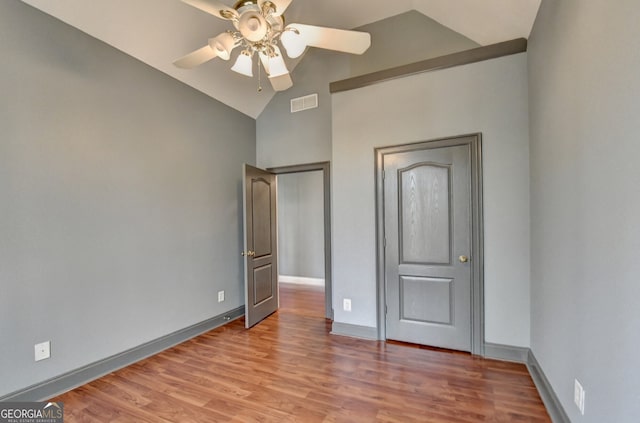 unfurnished bedroom featuring visible vents, baseboards, wood finished floors, and lofted ceiling