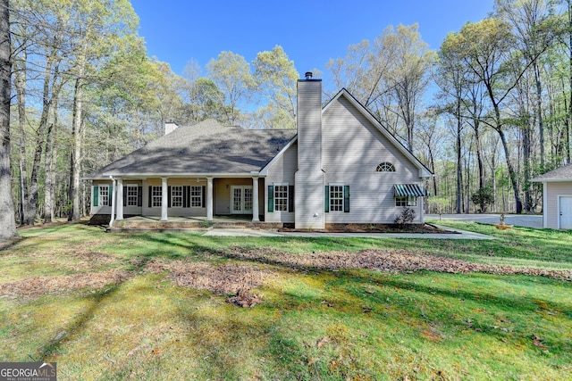 back of property with french doors, a chimney, and a lawn