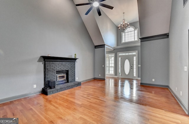 unfurnished living room with a fireplace, ceiling fan with notable chandelier, baseboards, and wood finished floors