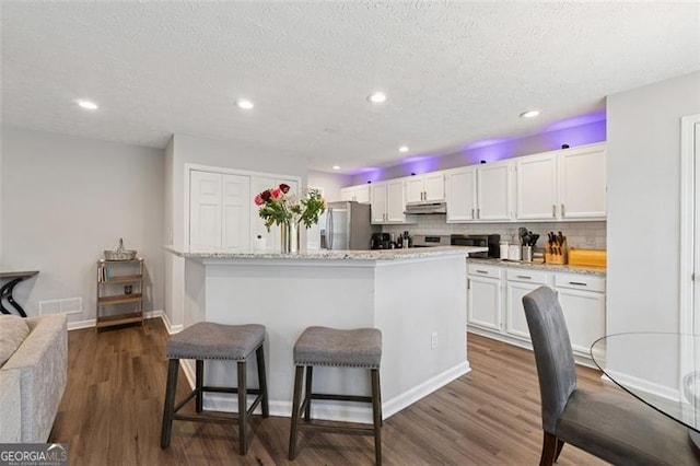 kitchen featuring dark wood-style flooring, white cabinetry, under cabinet range hood, and stainless steel appliances