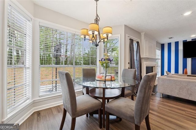 dining area with a textured ceiling, wood finished floors, an inviting chandelier, and baseboards