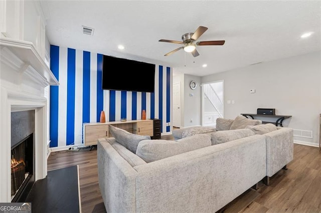 living room with dark wood-type flooring, visible vents, wallpapered walls, and an accent wall