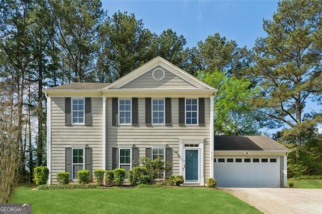 colonial-style house with a front yard, an attached garage, and driveway