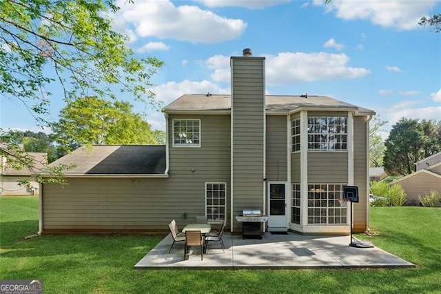 rear view of property featuring a patio, a yard, and a chimney