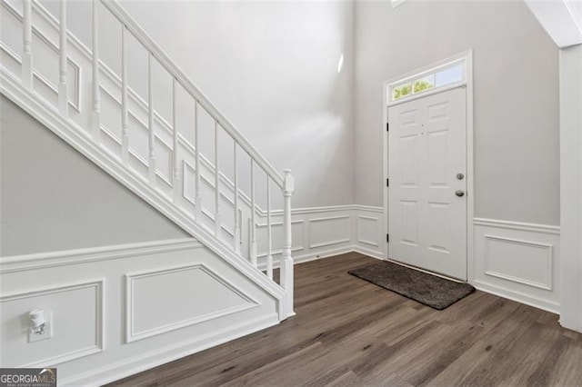 entryway featuring a decorative wall, stairway, a wainscoted wall, and wood finished floors