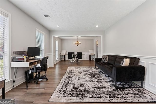 office with a chandelier, a textured ceiling, wainscoting, visible vents, and wood finished floors
