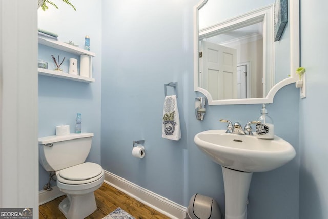 half bath featuring baseboards, toilet, and wood finished floors