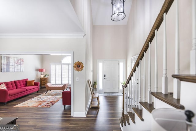 entrance foyer with crown molding, high vaulted ceiling, stairway, and wood finished floors