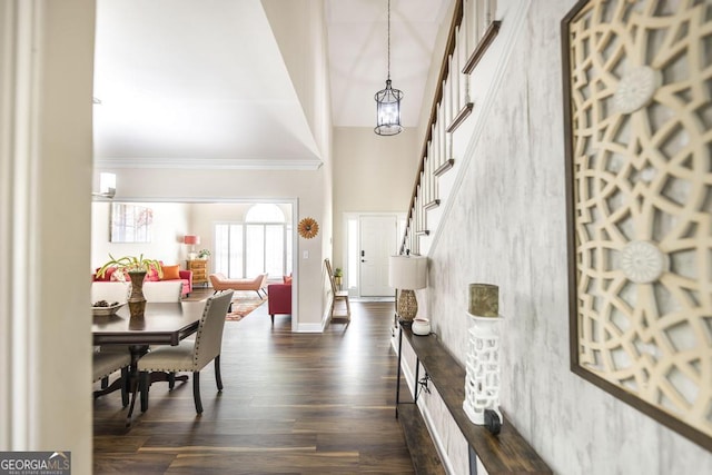 entrance foyer featuring a notable chandelier, baseboards, ornamental molding, dark wood-style floors, and a high ceiling