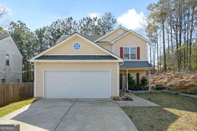 traditional-style house with an attached garage, a shingled roof, driveway, and fence