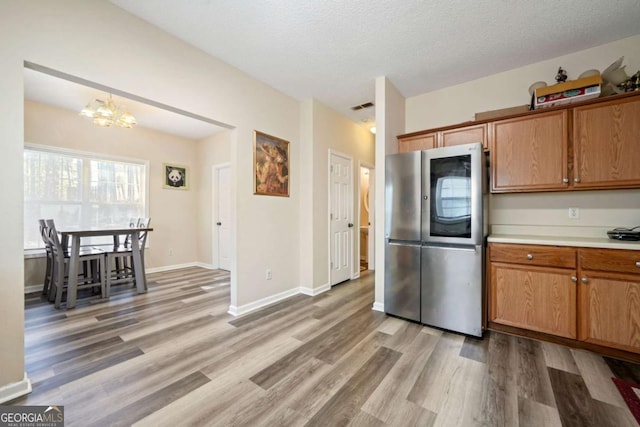 kitchen featuring visible vents, an inviting chandelier, light countertops, light wood-type flooring, and smart refrigerator
