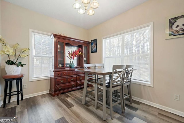 dining room featuring dark wood-type flooring, a notable chandelier, and baseboards