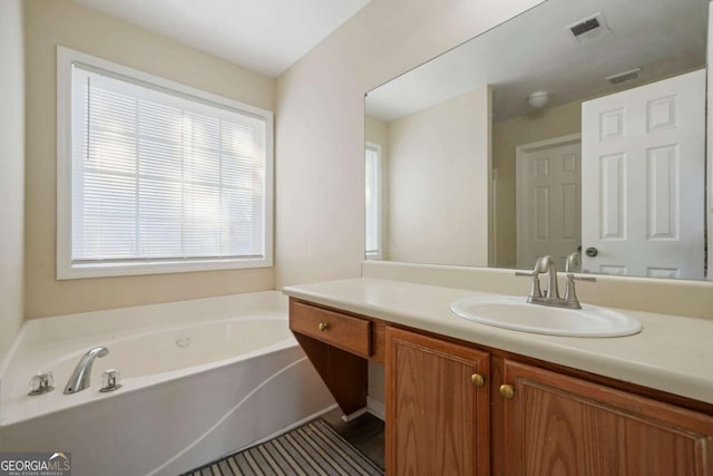 bathroom with a bath, vanity, and visible vents