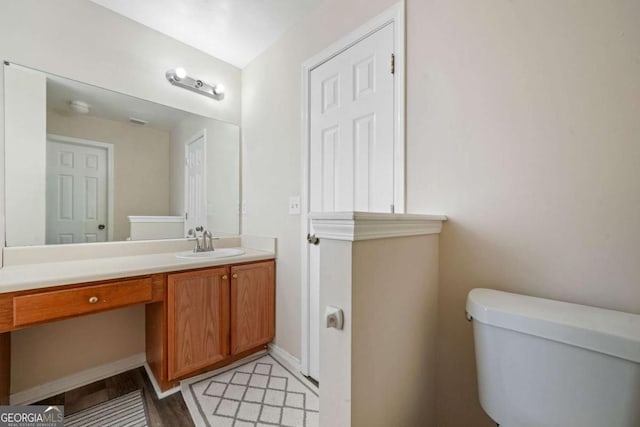 bathroom with vanity, baseboards, toilet, and wood finished floors